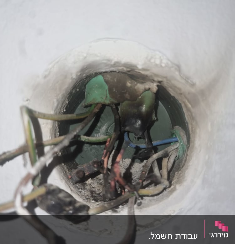 חוטי חשמל שרופים בתוך קופסת חיבורים בקיר